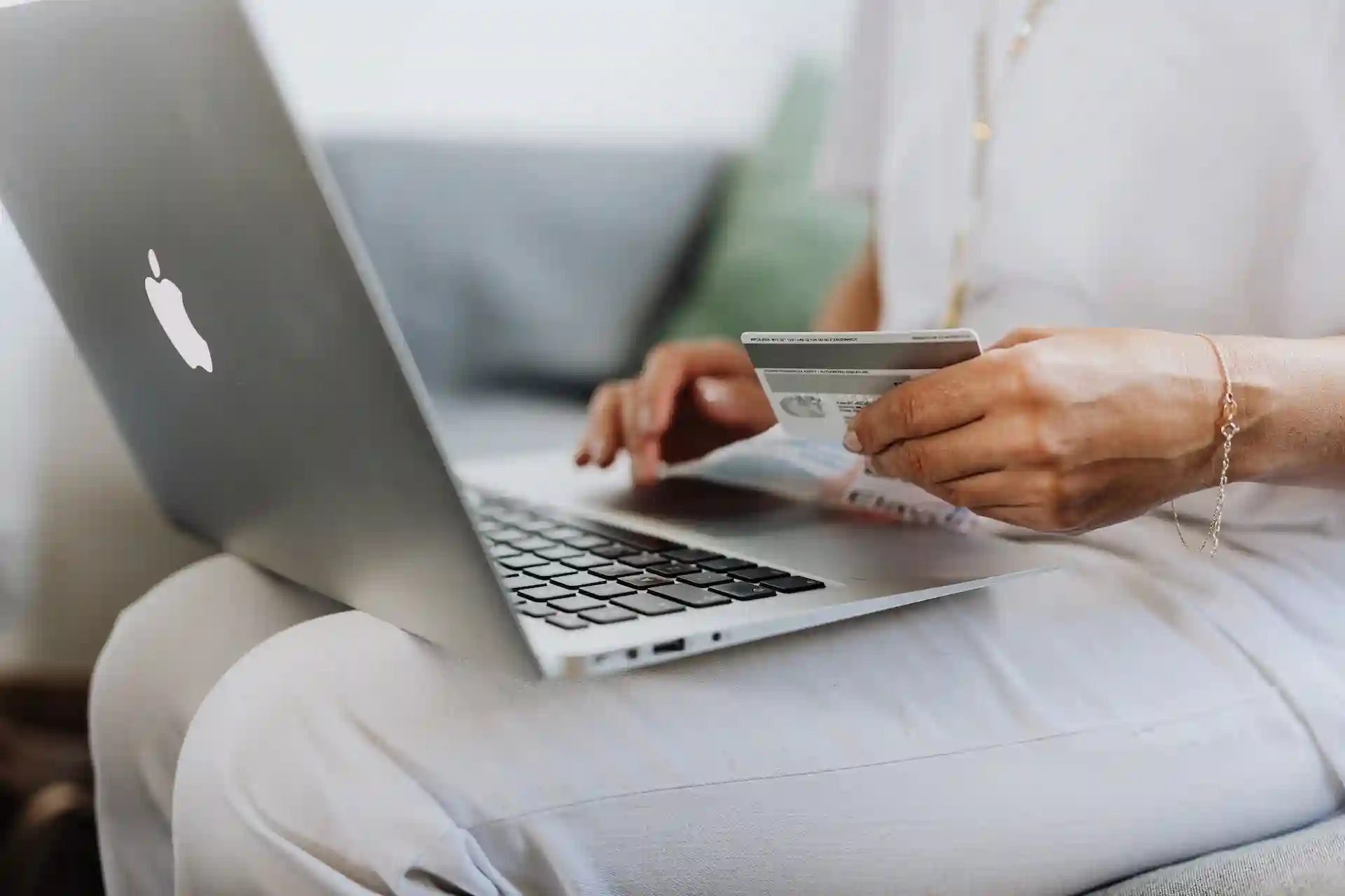 A woman holding a credit card while using a laptop to shop online.